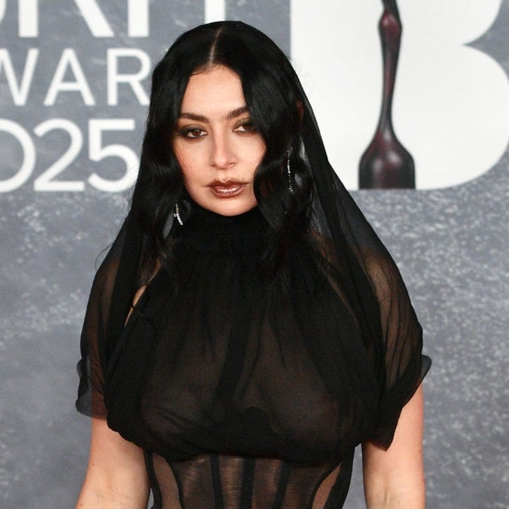 A person in sheer, fitted gown with dark hair styled in waves poses at a 2025 award event