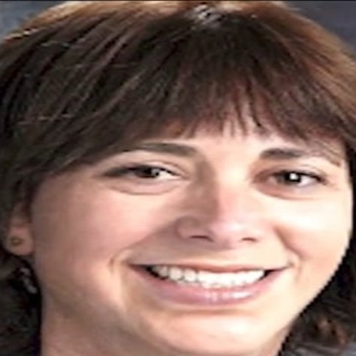 I don't know who this person is, but the image shows a portrait of a smiling woman with short hair. There's a small news graphic in the top left corner